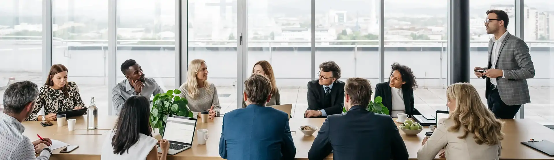 Business man presenting to a conference room table full of colleagues.