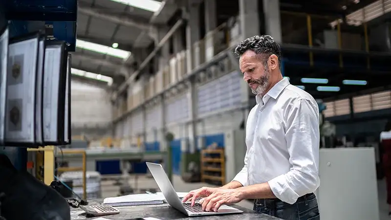 Business man working on a laptop in a warehouse