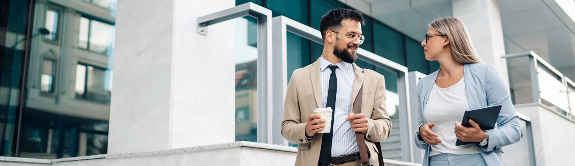 Male and female colleagues walking, drinking coffee and talking about ethical financial services and does U.S. Bank have offices in Europe. 