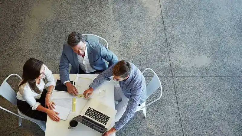 Top-down view of three colleagues sitting around a table discussing fund administration 