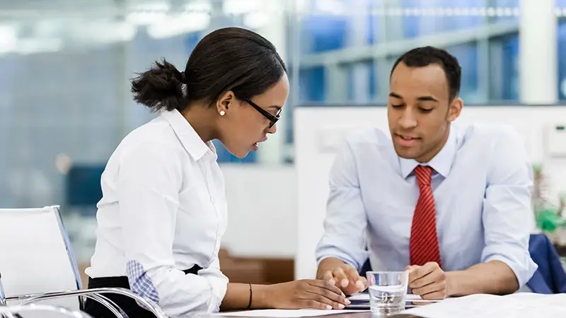 Male and female colleagues at a table discussing AML law Luxembourg
